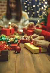 Young woman tighten gorgeous bow on present box on desk as craft working to prepare luxury gift and beautiful ornament for Christmas party decoration to celebrate winter holiday in December