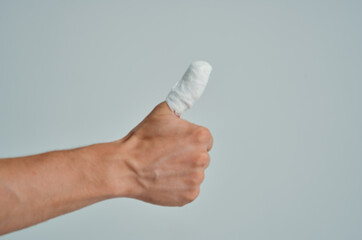 male patient bandaged hand injury to fingers light background