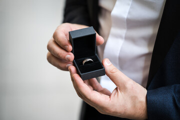 Groom holing beautiful modern wedding rings with jewellery box open before wedding ceremony.