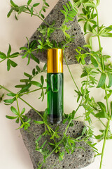 a green cosmetic product on a stone podium with green plants on a beige background. aromatic oil on a stone podium. organic cosmetic products. Healthy cosmetology, spa treatment concept
