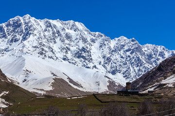 Fototapeta na wymiar View of the Ushguli village at the foot of Mt. Shkhara. Lamaria Monastery, old Rock tower