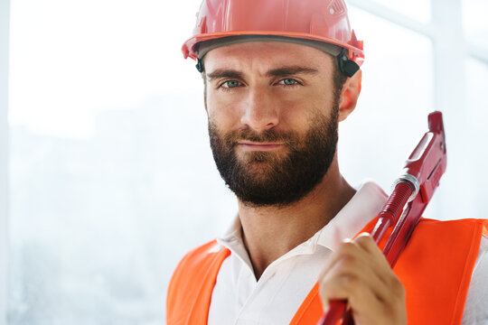 Young Male Plumber Holding Pipe Wrench On A Construction Site Indoors