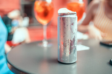 Summer cold aluminum can with alcoholic drink and decor on the table and light bokeh in an outdoor pub