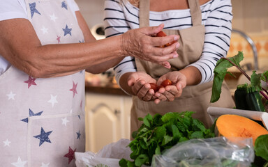 Pair of female hands holding small tomatoes. A mix of fresh vegetables on the kitchen table