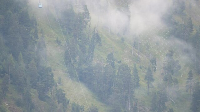 Two cable cars of the Herzogstandbahn in Bavaria passing each other on cloudy day with fog