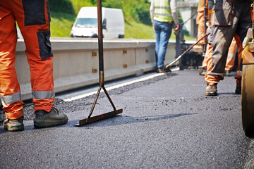 Workers in process of paving smoothing the road on a sunny day teamwork