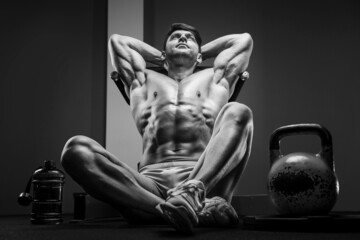 Fototapeta na wymiar Young athletic man pumping up muscles in the gym at workout. Sport and health care concept background
