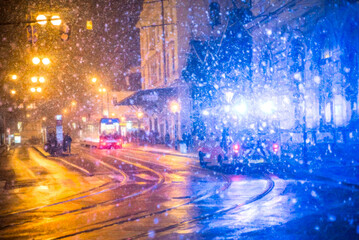 The tram goes in the evening in winter in Prague, it is snowing, an ambulance is coming to meet him.