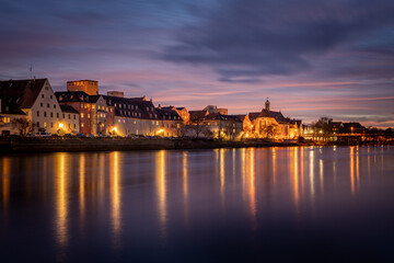 View from the Danube on the Regensburg Cathedral and Stone Bridge with lights in Regensburg in the evening, Germany