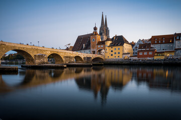 View from the Danube on the Regensburg Cathedral and Stone Bridge with lights in Regensburg in the evening, Germany