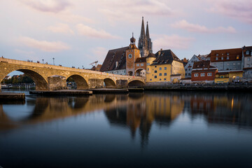 View from the Danube on the Regensburg Cathedral and Stone Bridge with lights in Regensburg in the evening, Germany