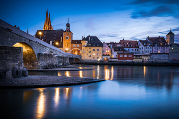 Fototapeta na wymiar View from the Danube on the Regensburg Cathedral and Stone Bridge with lights in Regensburg in the evening, Germany