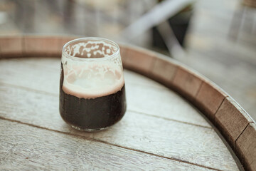Dark cold beer on wooden barrel with copyspace, selective focus in a street cafe
