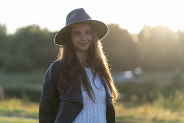 A woman in a hat smiles in the bright glow of sunset rays