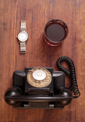 Retro style phone and whiskey glass on old wooden table