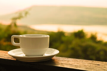 a white cup of coffee  with on sunrise time