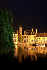 Romantic evening view of the canal, illuminated by old town lights and reflections in the water, Bruges, Belgium