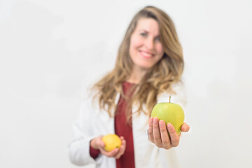 pretty Caucasian girl holding an apple . Nutritionist advising on healthy food