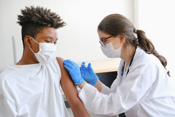 Caucasian doctor woman or nurse giving flu or antiviral vaccine to African American man in hospital or clinic