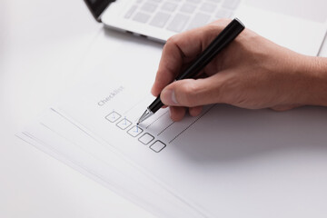 Close-up of businessman hand Checklist with pen, Filling Tasks to Checklist
