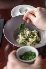 person eating pelmeni Dumplings with parsley and sour cream