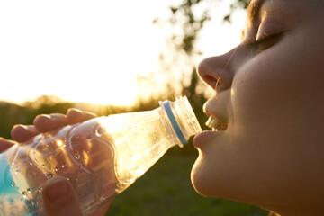 woman outdoors drinking water from a bottle of refreshment