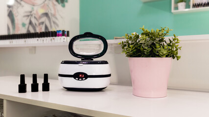a sterilizer for manicure tools is on the table by the mirror. Professional equipment for sterilization of manicure tools. Beauty salon.Ultrasonic sterilizer.

