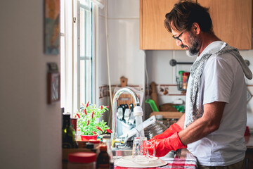 Bearded man cleaning utensils at sink in kitchen