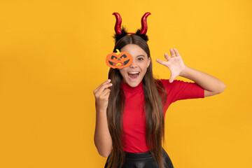 cheerful evil child in imp horns. happy halloween. devil kid with pumpkin party accessory