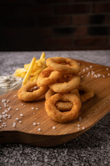 selective focus. fried onion rings in breadcrumbs fried in oil. with natural sauce. restaurant serving. on a dark background. for menus and ads