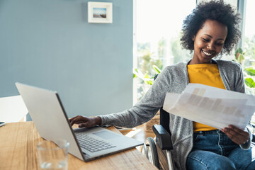 Young businesswoman reading document while sitting on wheelchair