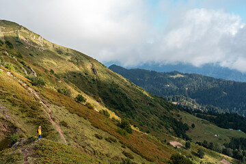 young woman in yellow hoodie in hood with backpack hiking in picturesque mountain valley healthy active lifestyle digital detox, weekend activities