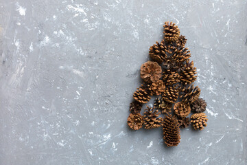 Christmas tree made from natural cones on colored background, view from above. New Year minimal concept with copy space