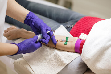 the doctor takes blood from a vein in the patient
