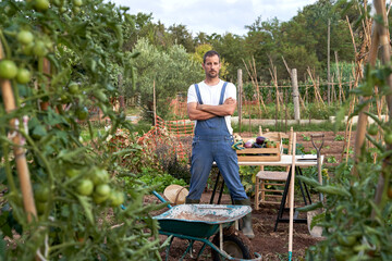 Confident farmer standing with arms crossed at agricultural field
