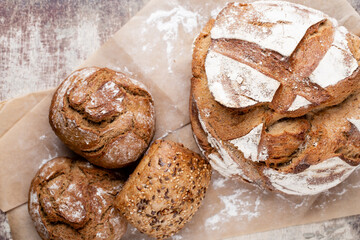 Gold rustic crusty loaves of bread and buns on wooden background. Still life captured from above top view, flat lay.