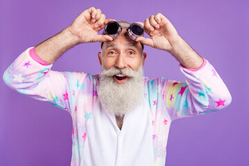 Portrait of attractive funny cheerful man touching pilot specs good mood isolated over violet purple color background © deagreez