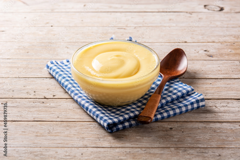 Wall mural pastry cream in a bowl on wooden table