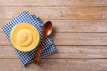 Pastry cream in a bowl on wooden table. Top view. Copy space