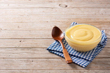 Pastry cream in a bowl on wooden table. Copy space