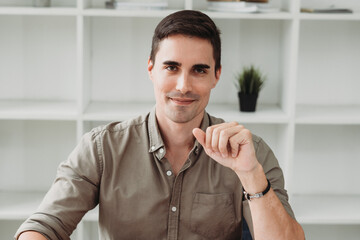 Smiling young guy taking selfie photo on smartphone on the office, Caucasian man using digital device. Selfie photo concept.