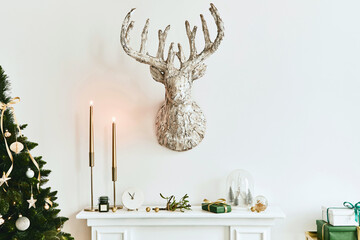 Christmas composition on the white chimney at the living room interior with beautiful decoration. Christmas tree and wreath, candles, stars, light. Copy space.  Template.