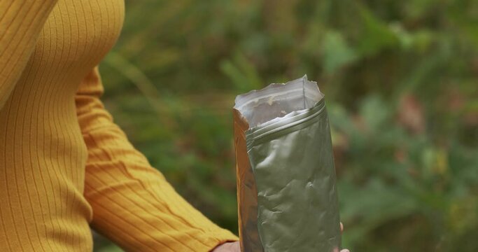 Hand picks up tourist freeze-dried food from a package. Camping food in nature. 