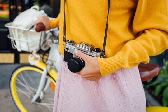 Young woman with bicycle holding camera