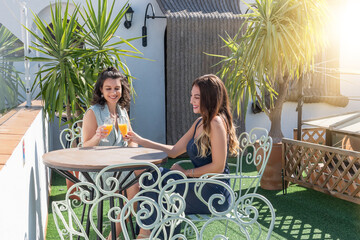 Two beautiful and young girls on vacation having an aperitif on a hotel terrace. Two women having a...