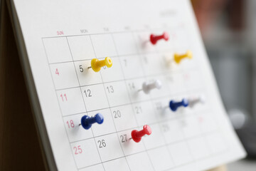 Various color thumb tack pins on calendar as reminder - obrazy, fototapety, plakaty