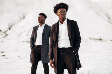 Two fashion models posing on the street, in classic clothes, fashionable African men, against the...