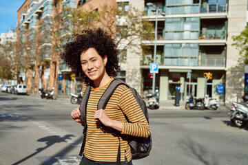 Fototapeta premium Smiling young woman crossing a street outdoors