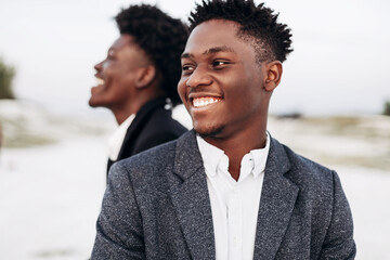 Two trendy African black men, outdoors, in stylish classic clothes, with fashionable hairstyle