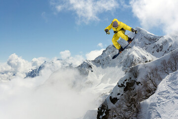 A jumping snowboarder in the mountains. Snowboarding, winter extreme sport.